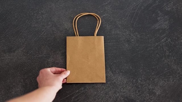 hand pushing away plastic wrapping and choosing paper bag instead