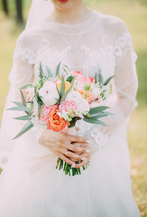 beautiful bouquet of different colors in the hands of the bride in a white dress