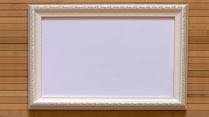 Fototapeta premium White frame with empty white canvas on natural bamboo wall. Horizontal picture 16:9 with useful design for input your inside text, image etc.