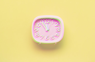 Pink alarm clock object on yellow background. Glitch style effect. Vibrant duotone yellow, violet colors. Top view.