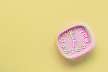 Pink alarm clock object on yellow background. Glitch style effect. Vibrant duotone yellow, violet colors. Top view.