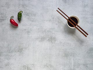 Two hot peppers and soy sauce with chopsticks. Food background.