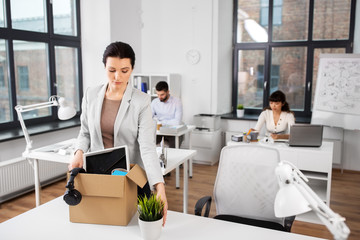 business, firing and job loss concept - sad fired female office worker with box of her personal...