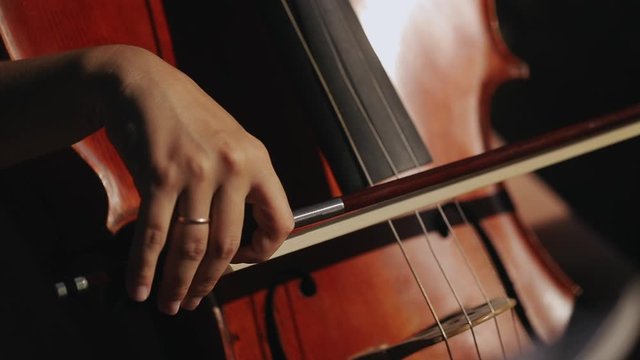 Young musician girl is playing at violoncello in symphonic hall. Shot in slow motion.