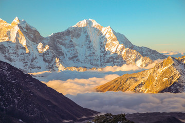 Obraz premium View of Tobuche mountain in the early morning from the summit of Kala Patthar in Nepal. The valley at the base of the mountain is covered with clouds. Nature, mountains, sunset and sunrise concept.