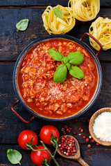 Traditional italian Bolognese sauce in saucepot an old dark wooden background. Top view, copy space