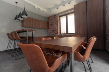 Interior of kitchen with dining table with cozy chairs next to cupboard and counter