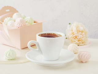 Pastel romantic background with coffee and small meringues in a box, flower and ribbons.