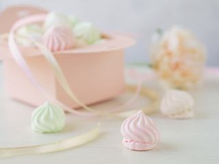 Pastel romantic background with small meringues in a box, flower and ribbons.