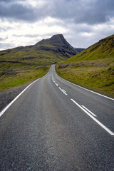 Dramatic landscape of Faroe Islands with remote road in a middle of mountains.
