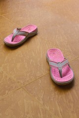Old Pink sandals Remove on the brown floor.