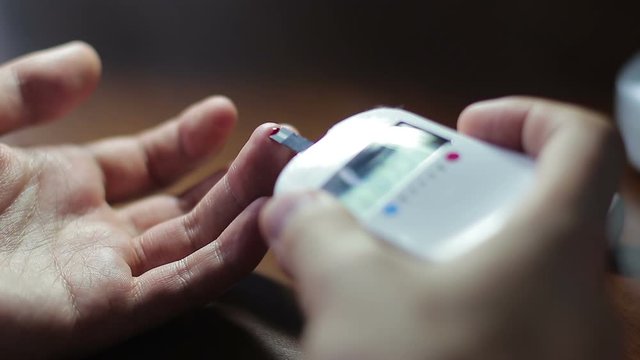 Diabetic man measures blood sugar level at home, close up