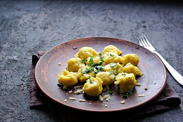 Pumpkin dumplings or gnocchi with parmesan cheese, butter and parsley on a brown clay plate. Harvest pumpkins. Thanksgiving Day. Selective focus. Italian food.