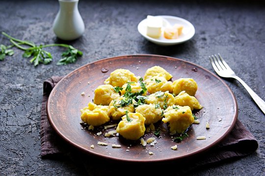 Pumpkin dumplings or gnocchi with parmesan cheese, butter and parsley on a brown clay plate. Harvest pumpkins. Thanksgiving Day. Selective focus. Italian food.