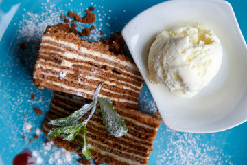 Ice cream ball and pieces of cake on a blue plate on a wooden background