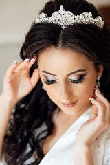 Fototapeta premium Beautiful bride portrait wedding makeup and hairstyle, girl in diamonds tiara, jewelry model, fashion bride gorgeous beauty. Close up portrait of Beautiful bride lowered her eyes down, shows makeup.
