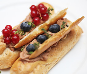 eclairs decorated with fresh berries on a white plate, handmade, culinary theme, close up