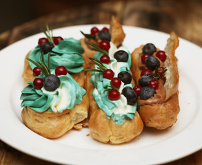 eclairs decorated with fresh berries on a white plate, handmade, culinary theme, close up