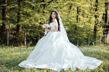 Obraz na płótnie Canvas Young beautiful stylish woman, bride, bridal fashion, spring trend, flowers, roses, hairstyle, beauty make-up, white dress. Wedding day. Happy bride in a beautiful dress walking in the park