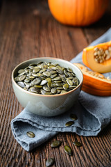 Pumpkin seeds in ceramic bowl, decorated with pumpkin slices
