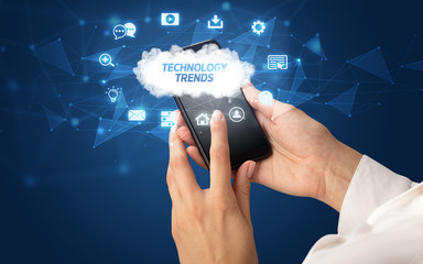 Female hand holding smartphone with TECHNOLOGY TRENDS inscription, cloud technology concept
