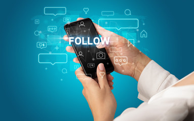 Female hand typing on smartphone with FOLLOW inscription, social media concept
