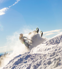 snowmobile jump. bright snowmobile in motion. the guy is flying on a snowmobile on a background of blue sky leaving a trail of splashes of white snow. bright snowmobile and suit without brands. super