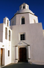 Fototapeta premium Daytime view of a pretty white church in Fira, Santorini, Greece. Santorini has many churches. The white church is against a blue sky. A white church in Fira, Santorini. White with blue sky. Santorini