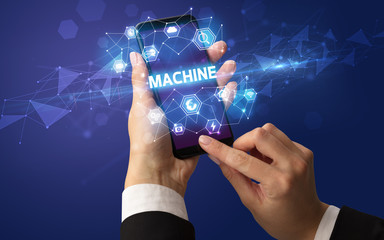 Female hand holding smartphone with MACHINE inscription, modern technology concept