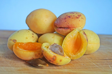 Ripe and juicy apricots and peaches with yellow and orange peels lie on a wooden table