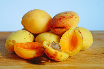 Naklejka na ściany i meble Ripe and juicy apricots and peaches with yellow and orange peels lie on a wooden table