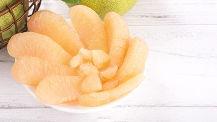 Fresh peeled pomelo, grapefruit, shaddock on bright wooden table background. Seasonal fruit for Mid-Autumn Festival, close up, copy space.