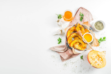 Autumn vegetarian food recipe. Organic roasted vegetables, Baked fried Hokkaido pumpkin with olive oil, herbs, garlic and honey. On a white stone background, copy space - obrazy, fototapety, plakaty