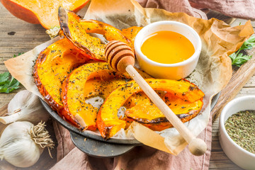 Autumn vegetarian food recipe. Organic roasted vegetables, Baked fried Hokkaido pumpkin with olive oil, herbs, garlic and honey. On wooden rustic background, copy space