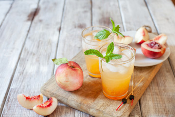 Peach cocktail with mint on white wooden background