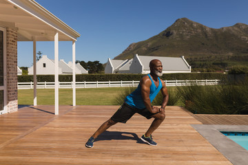 Senior man performing stretching exorcise in the backyard of home