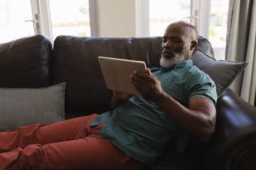 Obraz premium Senior man using digital tablet in living room