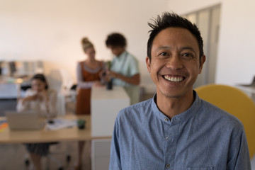 Obraz premium Smiling casual businessman looking at camera in office