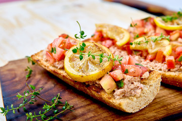 Appetizer bruschetta with tuna and tomatoes. Italian cuisine. Delicious Italian antipasti crostini on wooden board. Copy space.