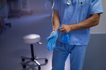 Male surgeon wearing rubber gloves in hand