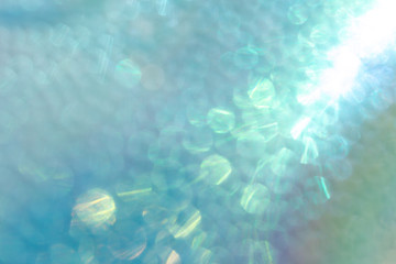 Abstract shiny iridescent turquoise background with holographic bokeh.