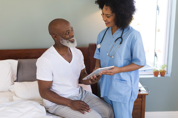 Senior man and female doctor using digital tablet at home