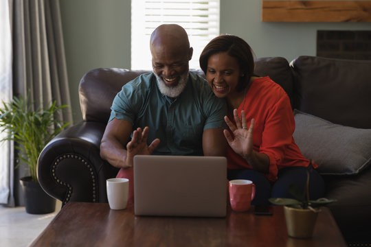 Senior Couple Making Video Call On Laptop In Living Room