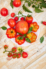 Mix of tomatoes background. Beautiful juicy organic red tomatoes on white wooden table background. Clean eating concept. Copy space, flat lay..