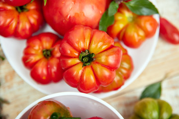 Mix of tomatoes background. Beautiful juicy organic red tomatoes on white wooden table background. Clean eating concept. Copy space, flat lay..