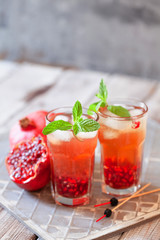 Fototapeta na wymiar Mojito cocktail with pomegranate, mint, lemon juice and ice