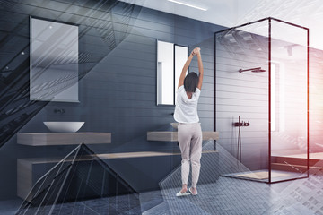 Woman in gray bathroom with shower and sink