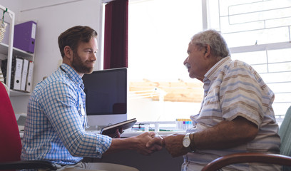 Male doctor and senior man interacting with each other in clinic