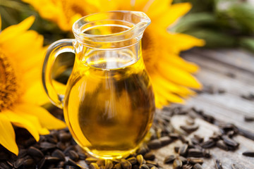 Organic sunflower oil in a glass jug, with sunflower seeds and fresh flowers. 