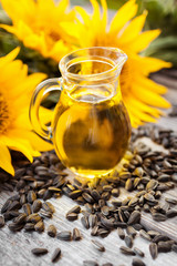 Organic sunflower oil in a glass jug, with sunflower seeds and fresh flowers. 